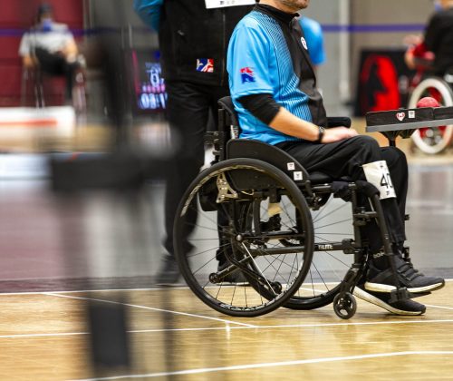 Close up of a person in a wheelchair, wering a blue shirt and black pants, during boccia championship at the Québec City Convention Centre.
