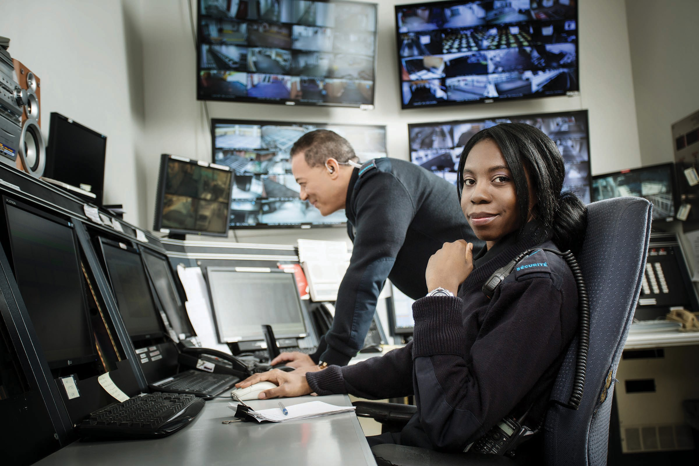 Deux agents de sécurité dans leur poste de commandement, devant leurs écrans.