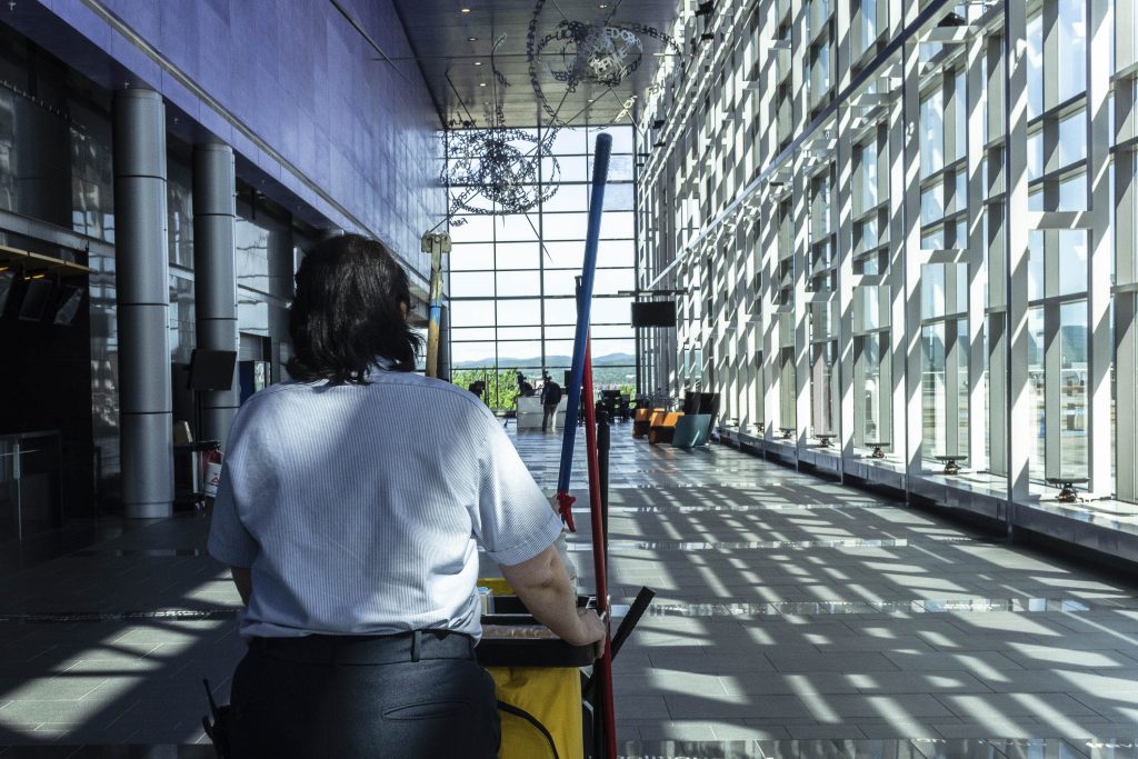 Une employée de l'entretien ménager qui fais sa tournée du grand hall avec son chariot.