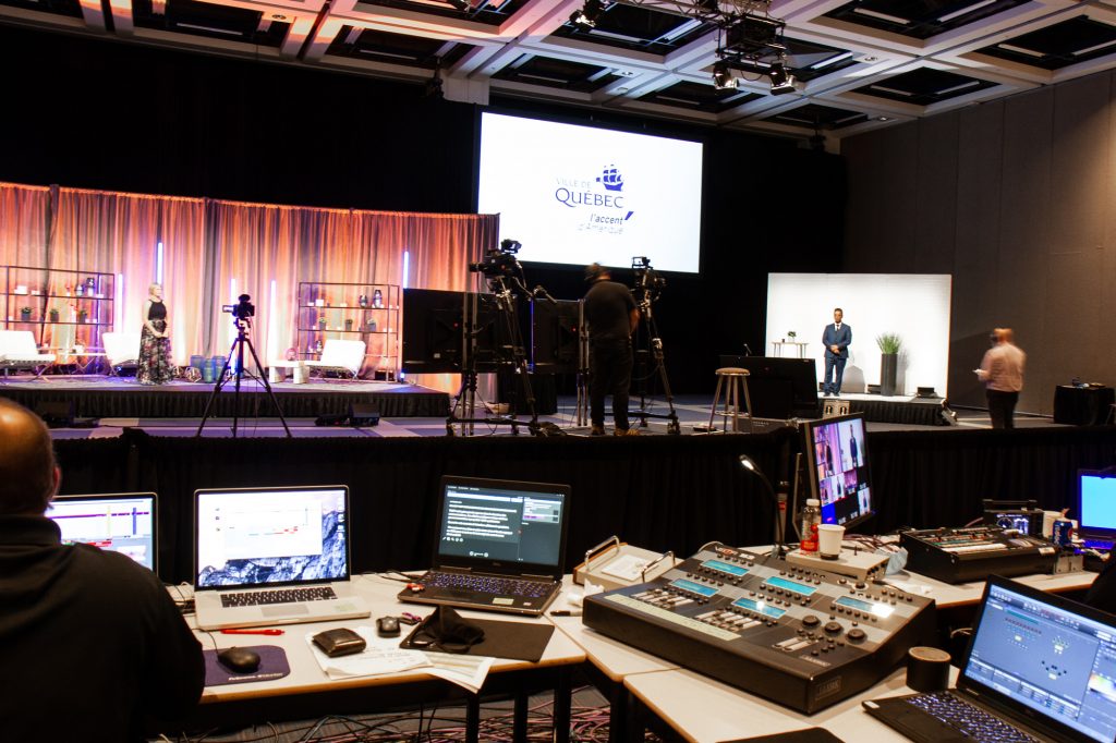 Événement virtuel en cours de tournage dans la salle 2000. On y voit les consoles audiovisuelles, les caméras et le plateau de tournage sur la scène.