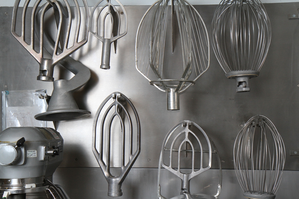 Set of pastry whips of different sizes, hung on a wall in the kitchens of the Québec City Convention Centre.