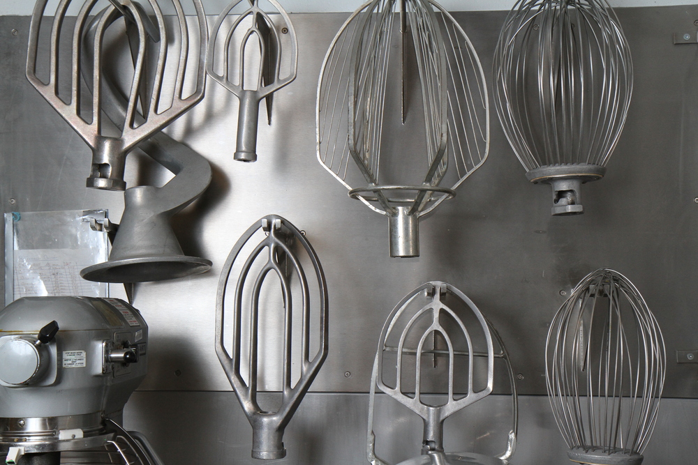 Ensemble de fouets de pâtisserie de différents formats, accrochés sur un mur des cuisines du Centre des congrès de Québec.