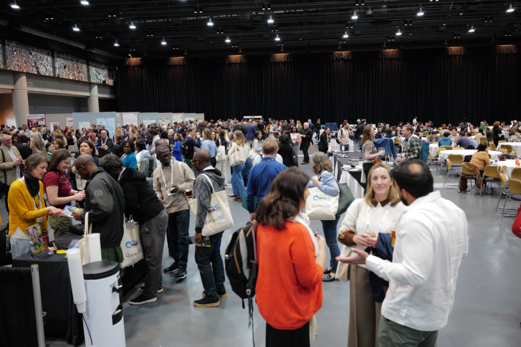 Activité de type "Poster Session" se déroulant dans la salle 400 lors du congrès international IAIA26. On peut voir des gens debout qui discutent, la salle est remplie de gens.