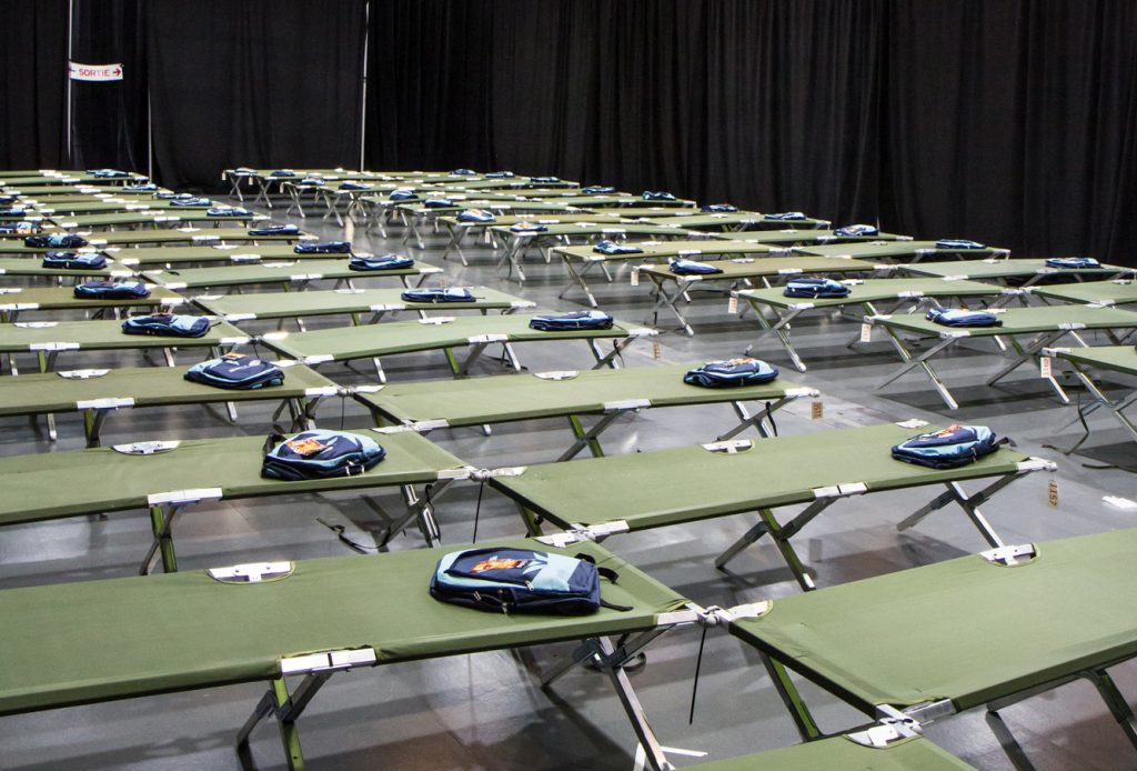 Salle transformée en dortoir pour les Jeux du Québec. On y voit des lits de camp, chacun d'eux a un sac des JDQ pour les jeunes.