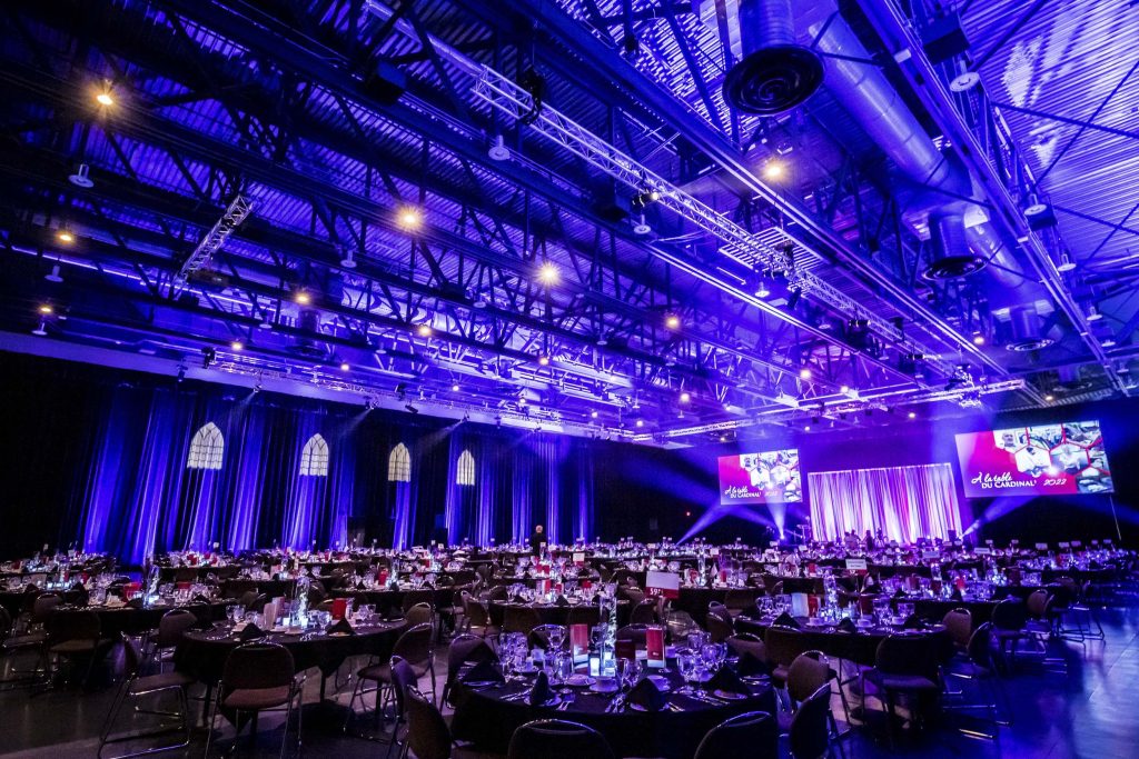 Large event room set up for a banquet with large sceens, stage and lighting