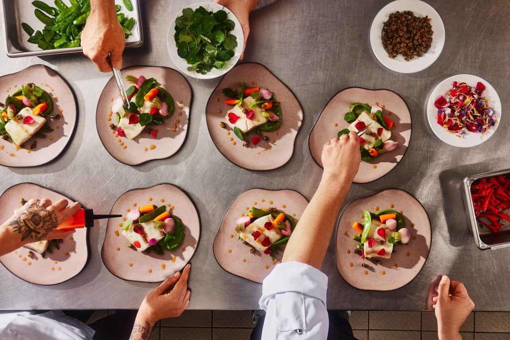 A few plates laid out on a table, while being finalized by the Maestro Culinaire team.