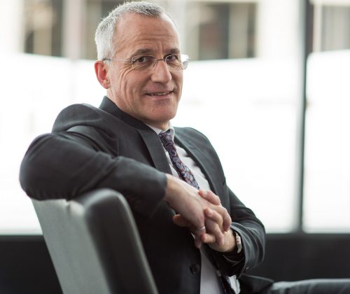 Man in suit sitting and smiling at the camera.