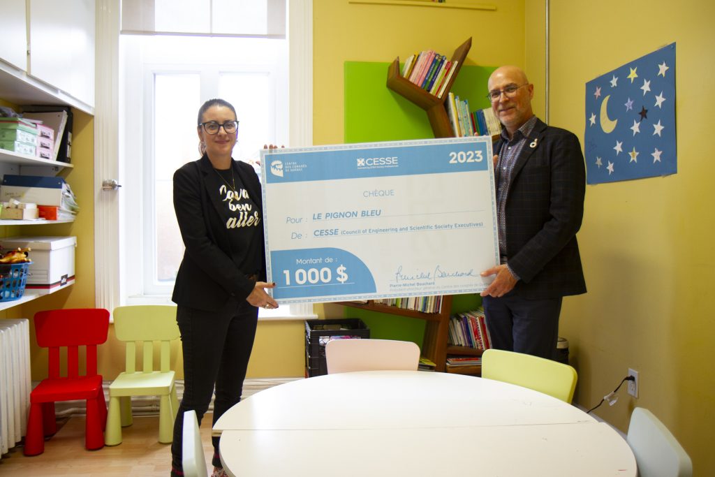 Jocelyn du Centre des congrès tiens un chèque géant avec la directrice du Pignon bleu.