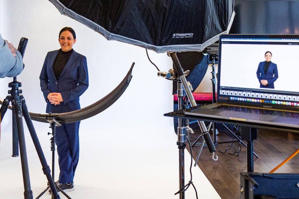 Femme portant le nouvel uniforme du Centre des congrès, durant une séance photo officielle. On peut voir le bras du photographe, son appareil et son matériel, entre deux prises de photo.