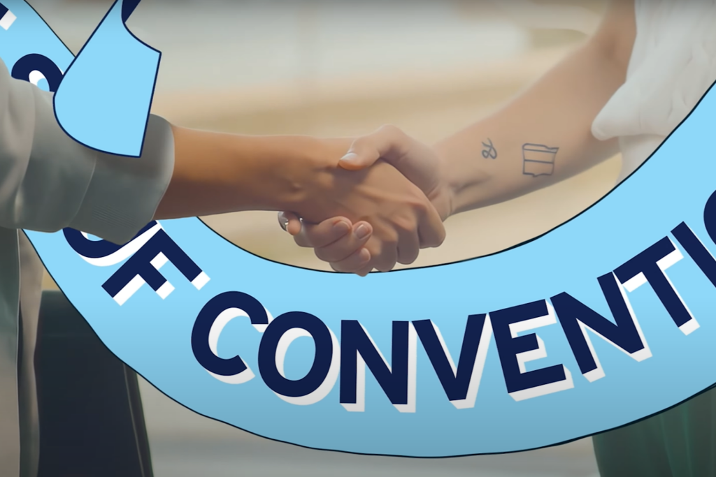 Thumbnail from the promotional video “Anything but Conventional,” showing two women shaking hands, which activates the “Anything but Conventional” mode.