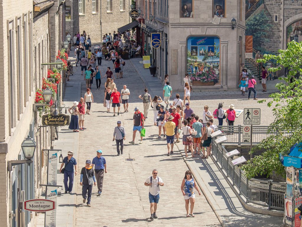 Rue du Vieux-Québec animée, par une journée ensoleillée, avec des piétons, des familles, des touristes.