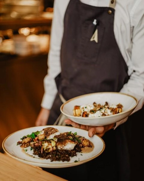 Server holding 2 plates at Québec City Restaurant Chez Boulay.