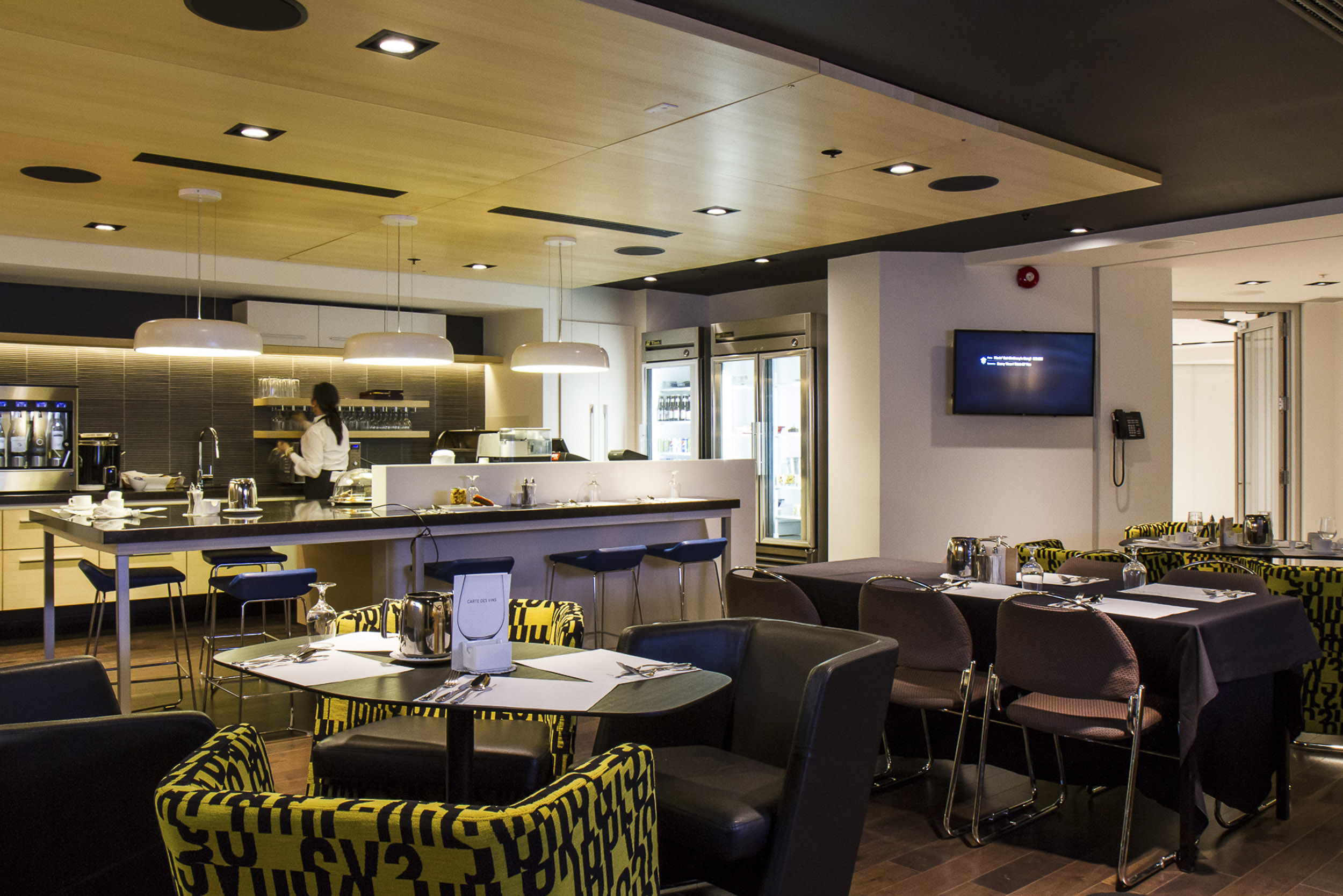 Restaurant with tables and chairs, and tv on the wall.