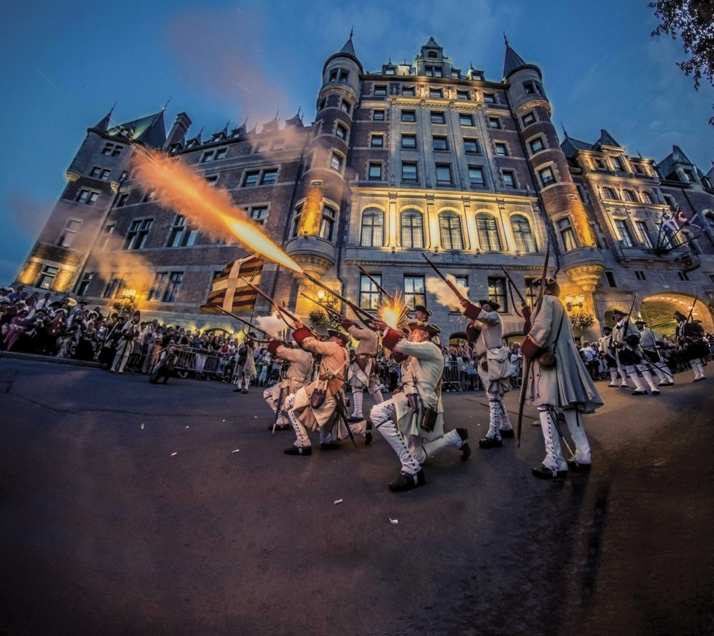 Hommes en costume d'époque avec des carabines, devant le Château Frontenac. Ils donnent des coups de feu pour impressionner les festivaliers des Fêtes de la Nouvelle-France.