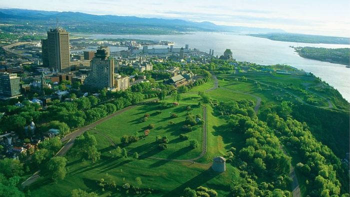 Aerial view of the Plains of Abraham in summer, with the Martello Towers. In the distance, the Château Frontenac and the St. Lawrence River can be seen.