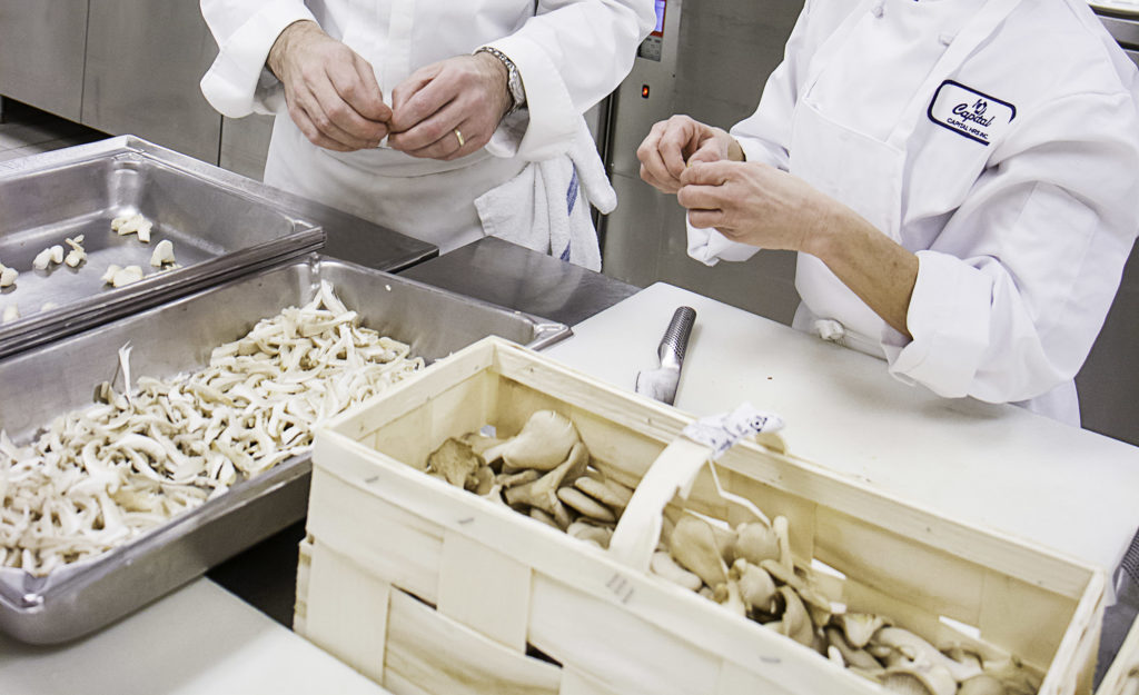 2 cuisiniers qui préparent des champignons en cuisine.